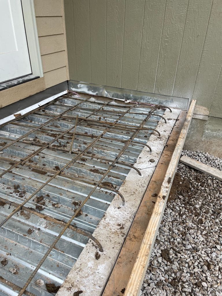 A concrete deck is being built in front of a house.