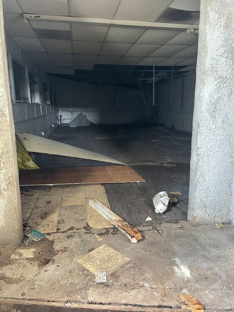 An empty room with a lot of trash on the floor.