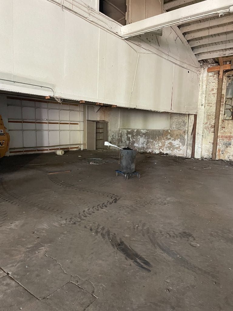 An empty warehouse with a vacuum cleaner on the floor.