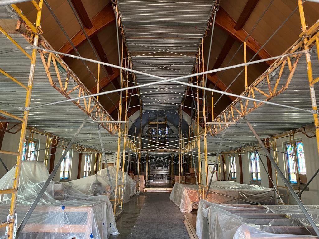 The inside of a building under construction with scaffolding hanging from the ceiling.
