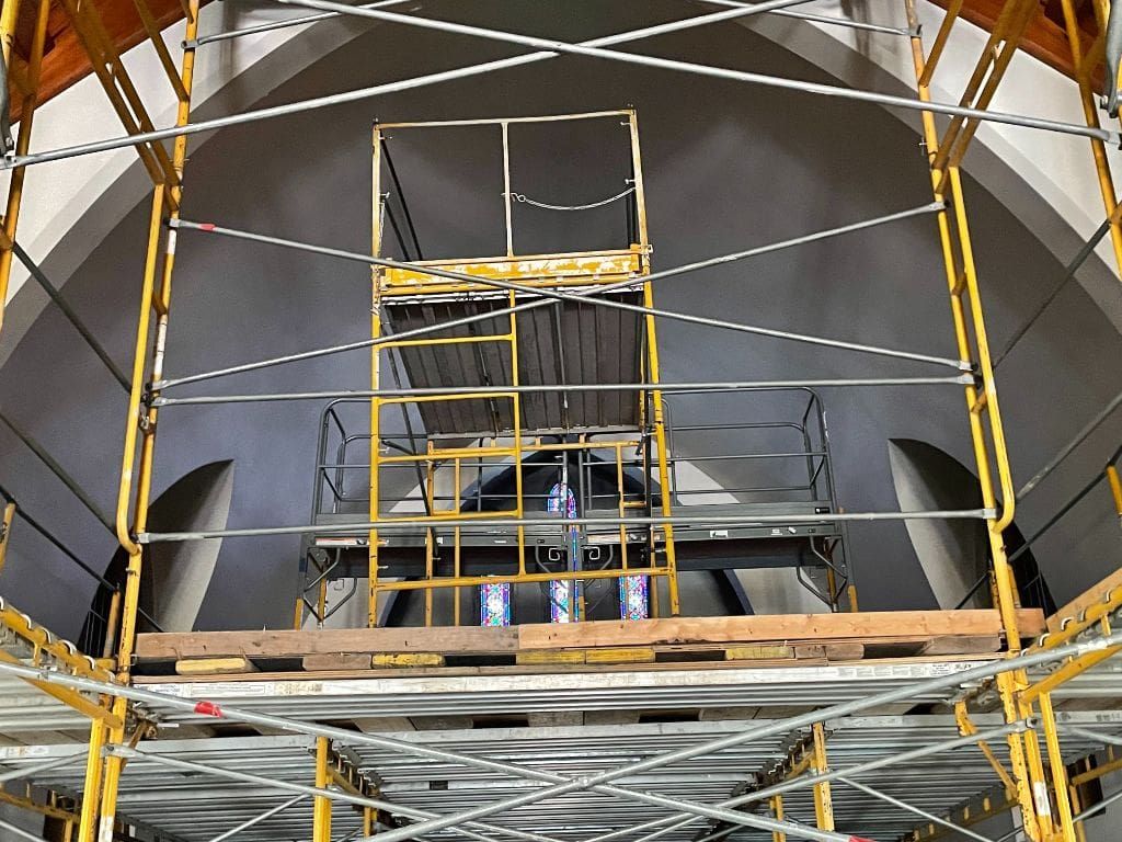 A large building under construction with scaffolding and a ladder.