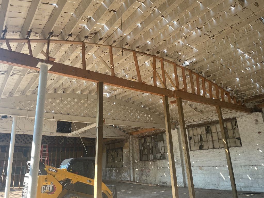 A yellow cat skid steer is parked in a building under construction