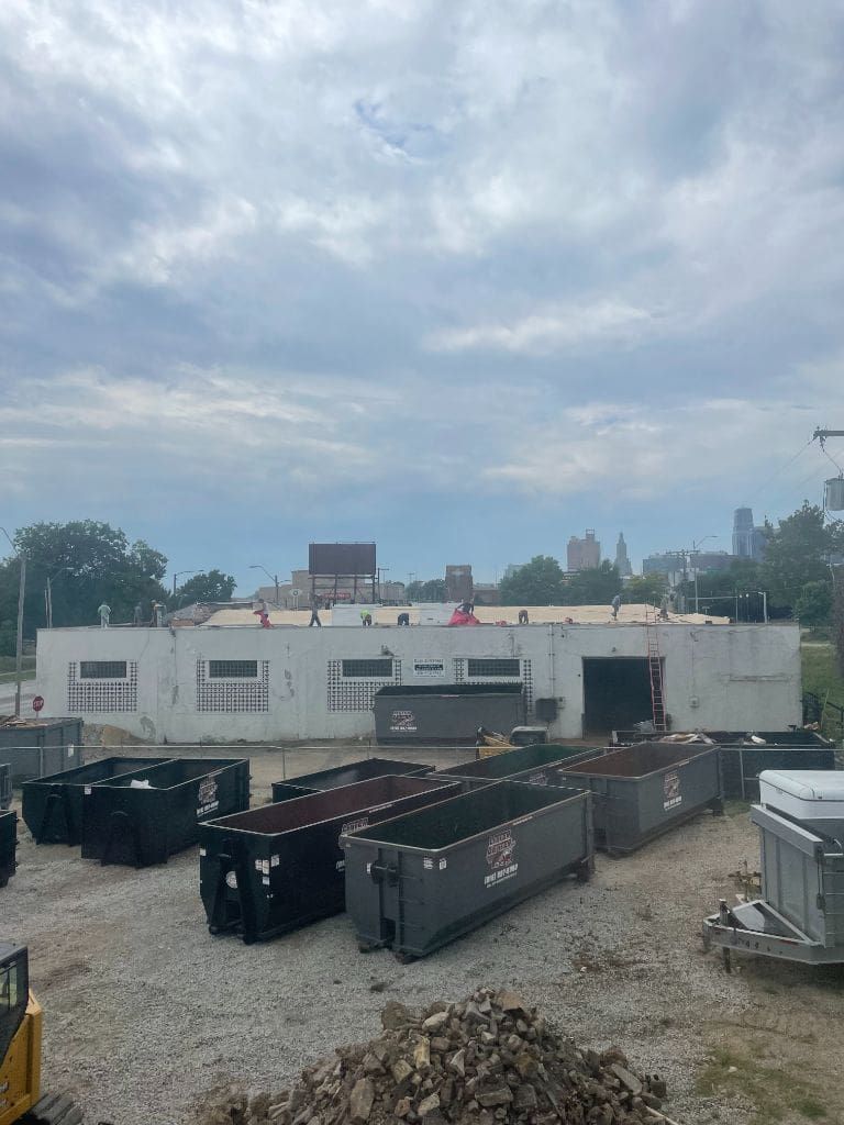 A lot of dumpsters are lined up in front of a building