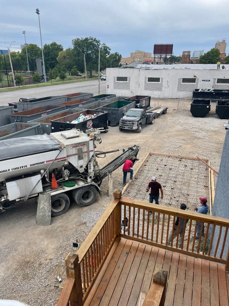 An aerial view of a construction site with a tanker truck and a concrete pump.