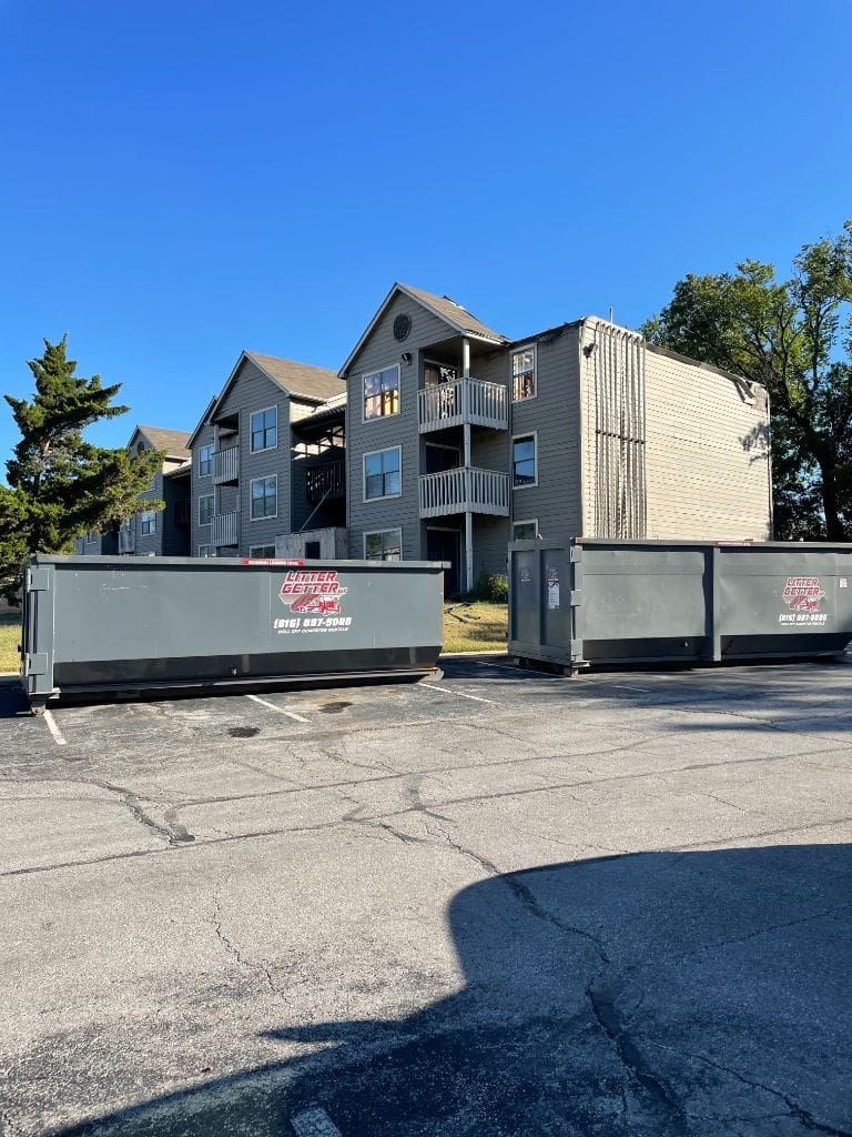 A couple of dumpsters are parked in front of a building.