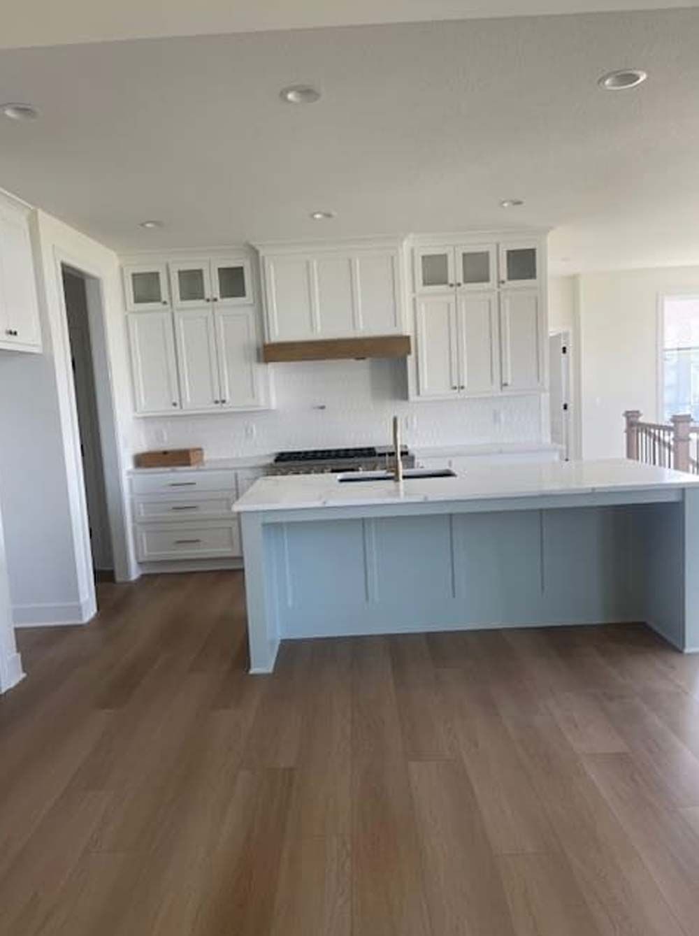A kitchen with white cabinets and a wooden floor.