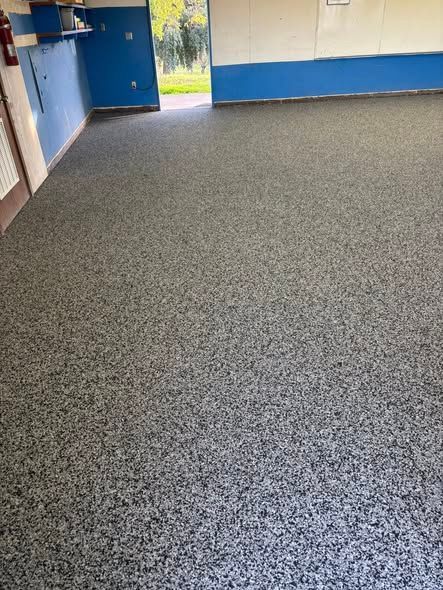 Room with speckled gray flooring, blue walls, and an open doorway to the outside.