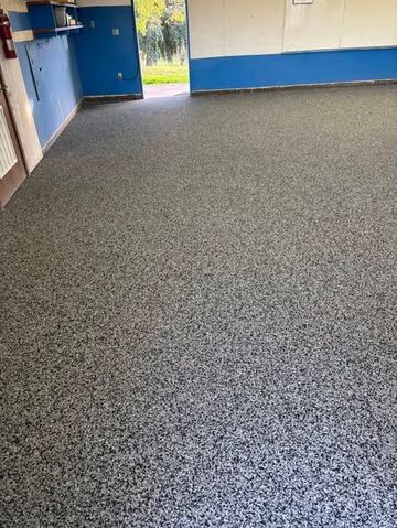 Room with speckled gray flooring, blue and white walls, and a doorway to the outside.