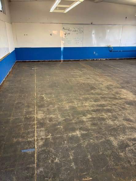 Empty room with blue and white walls, dark floor, and overhead lighting.