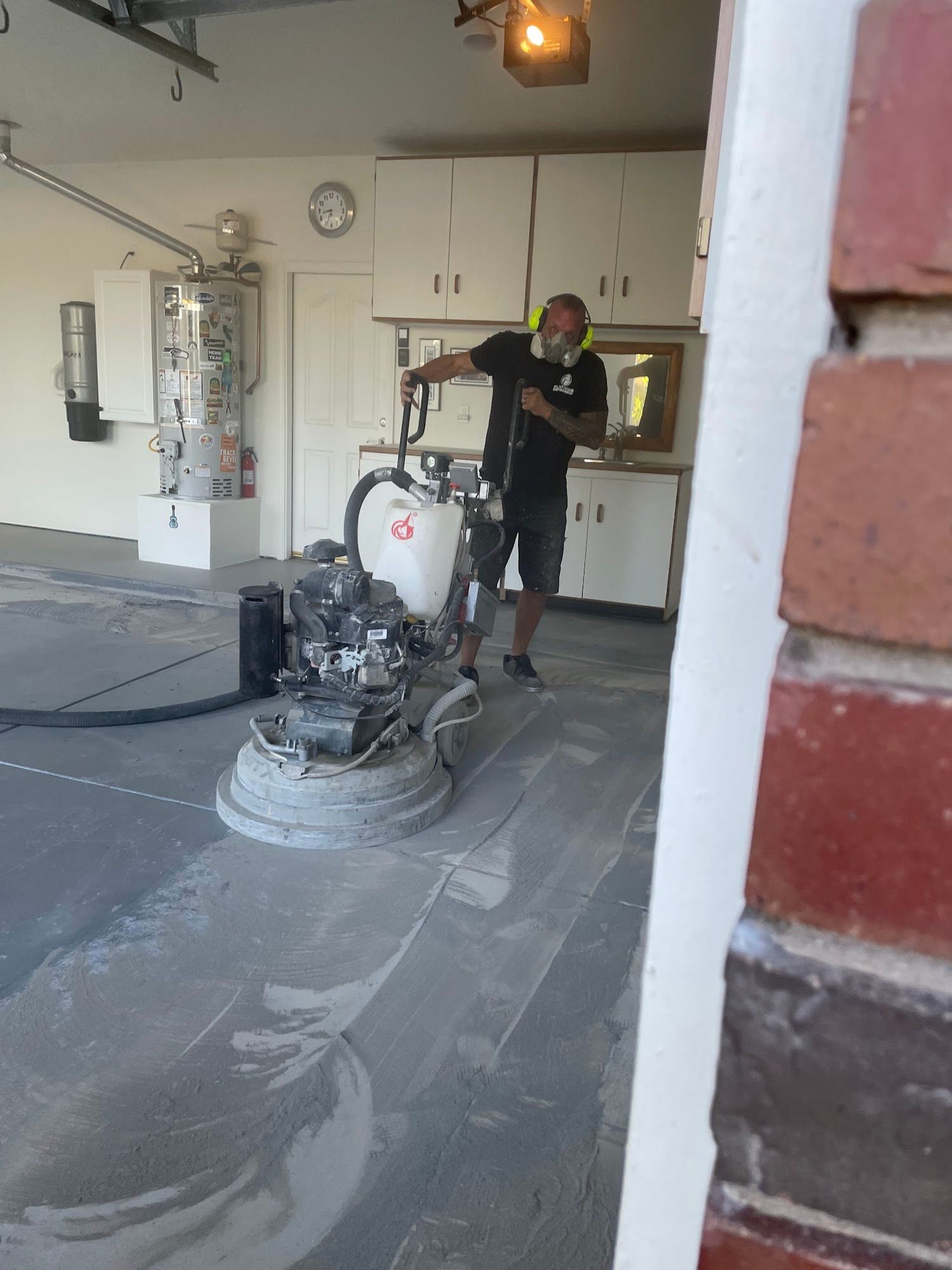 Person grinding a concrete garage floor with a machine.