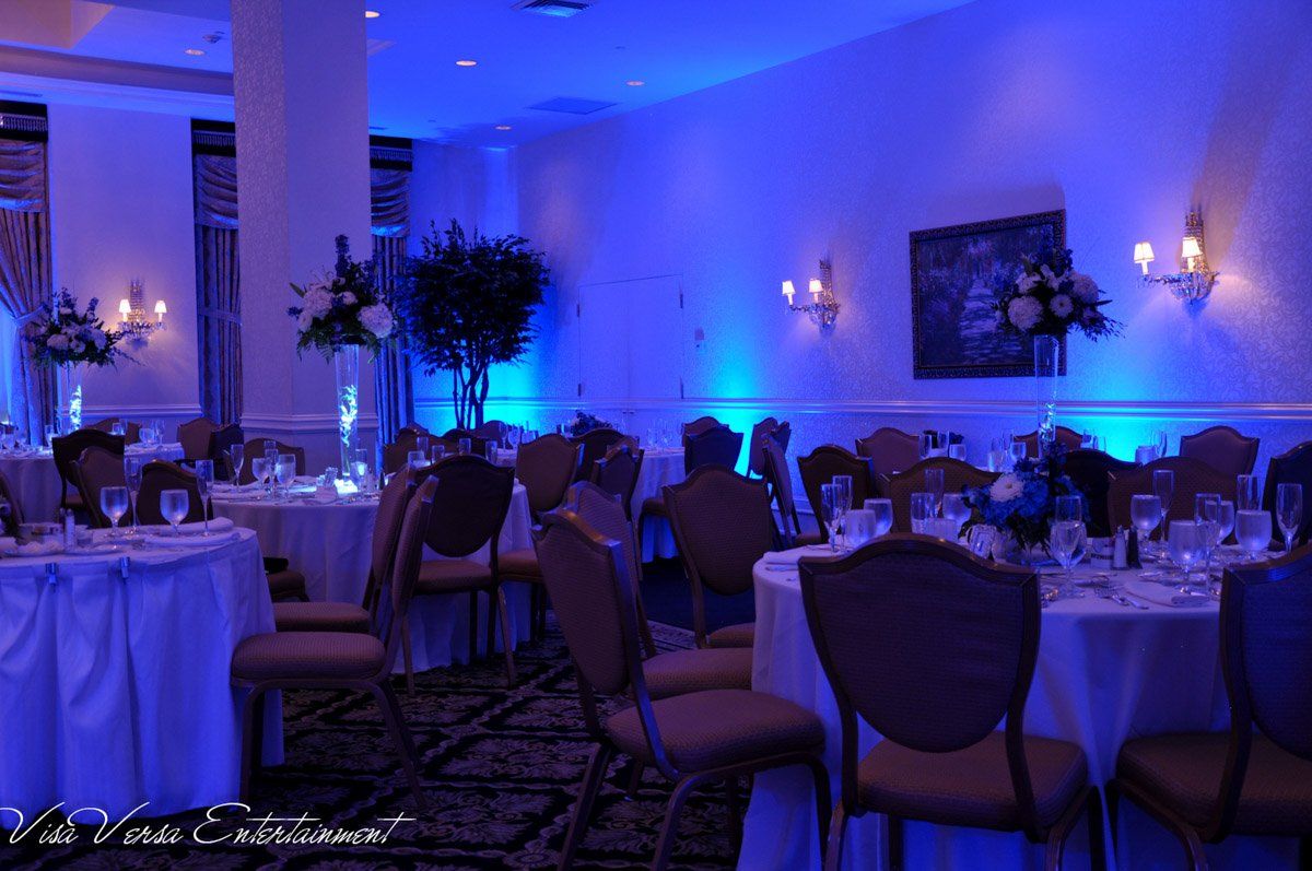 A banquet hall illuminated in blue, round tables set for a formal event.