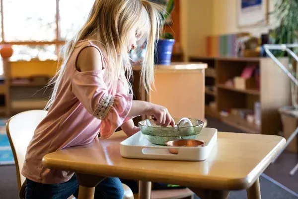 A little girl is sitting at a table playing with toys.