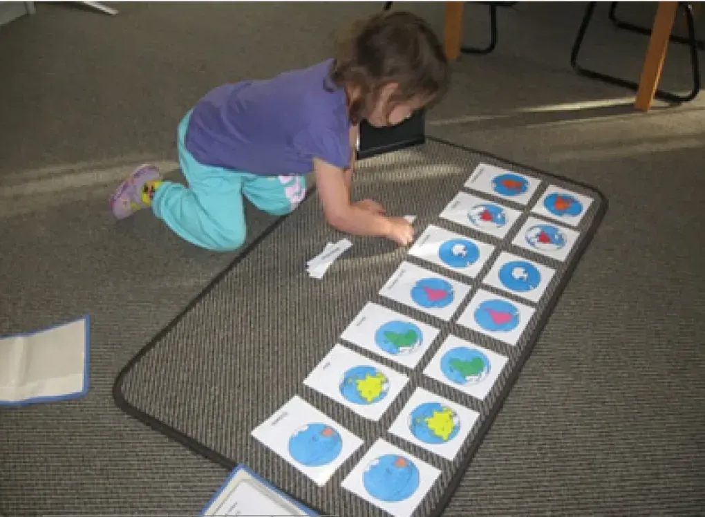 A little girl is kneeling on the floor playing with cards