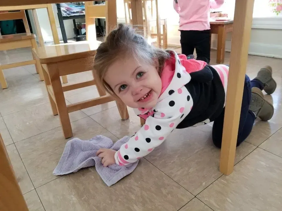 A little girl is cleaning the floor with a towel