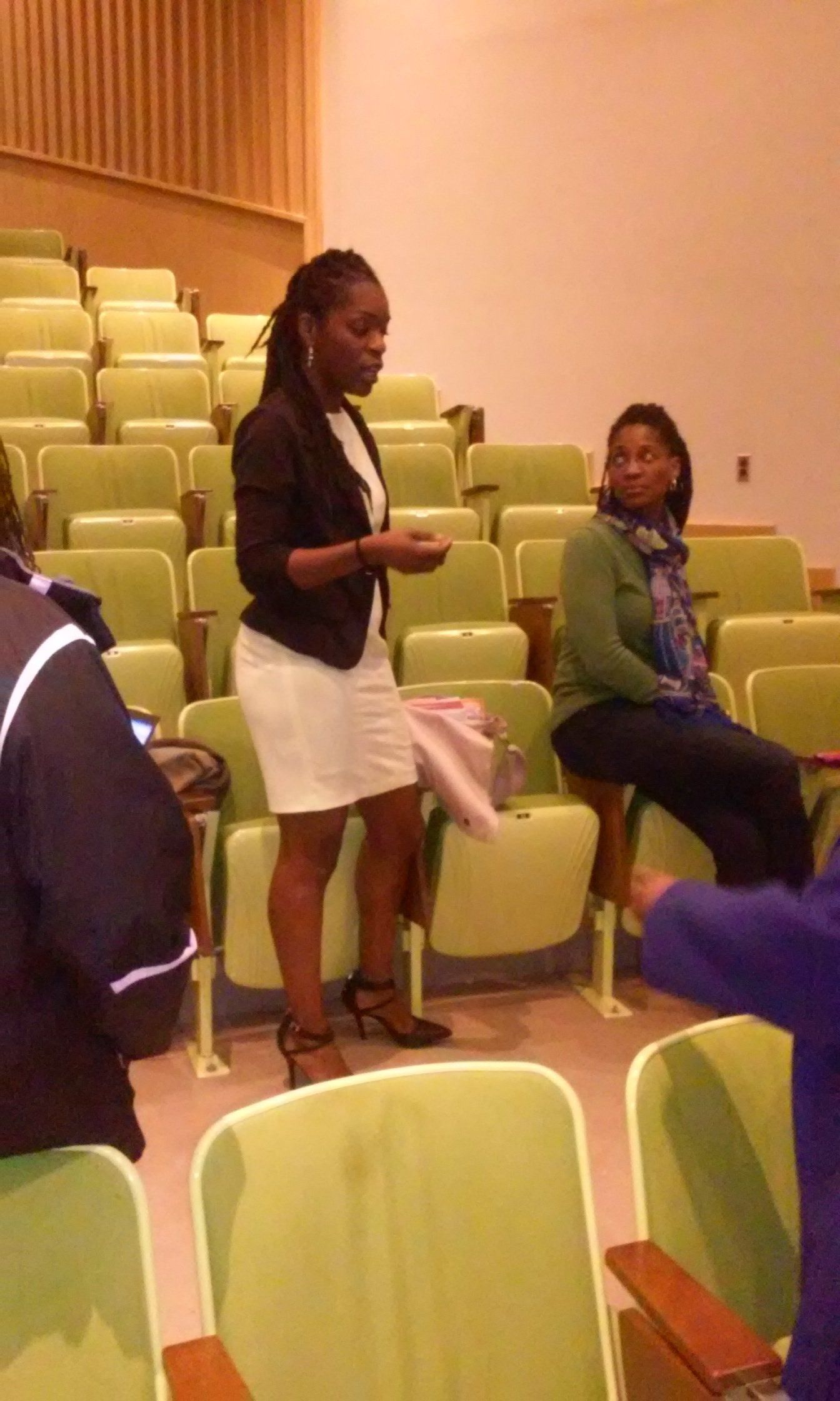 A woman is standing in an auditorium holding a piece of paper