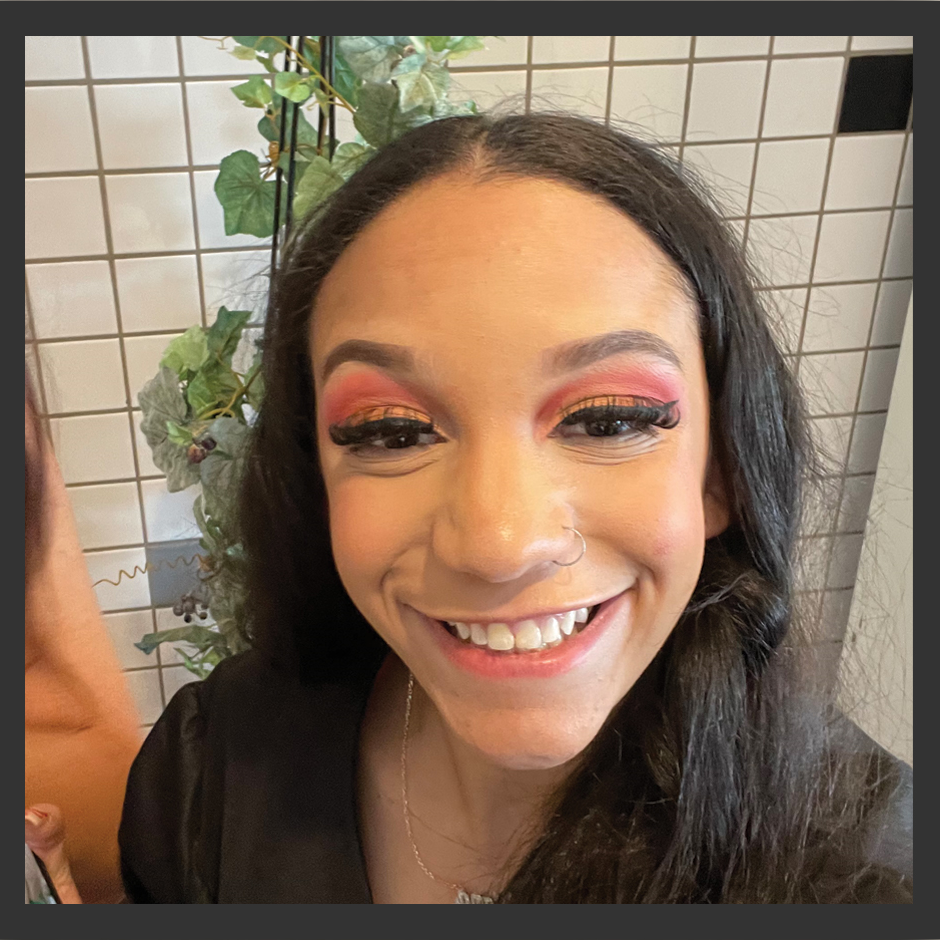 A woman wearing red eye shadow is smiling for the camera.