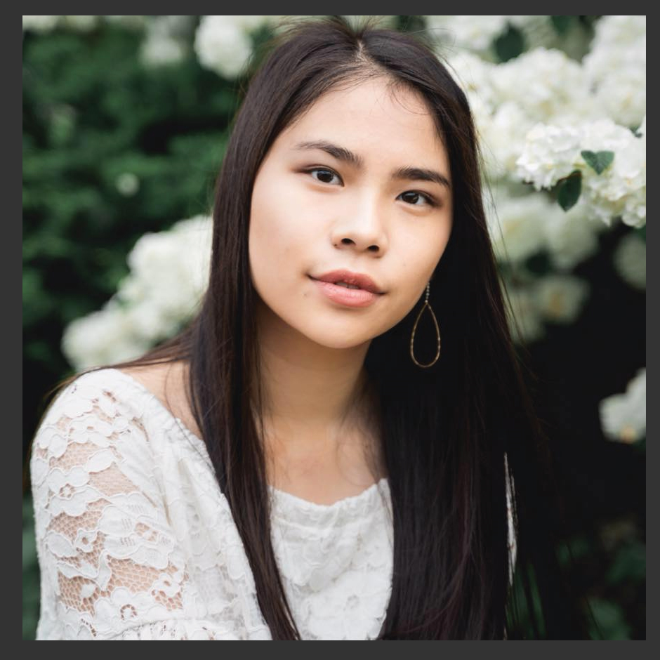 A woman with long hair is wearing a white lace top and earrings.