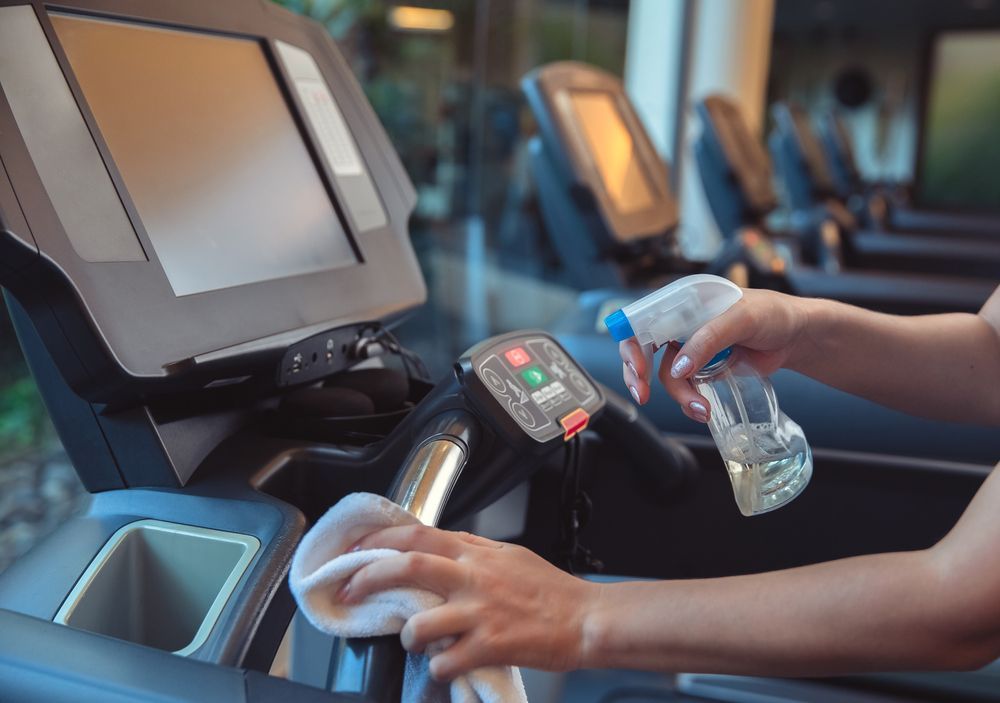 A Person Is Cleaning A Treadmill In A Gym — DP Cleaning Supplies Pty Ltd In Mareeba, QLD