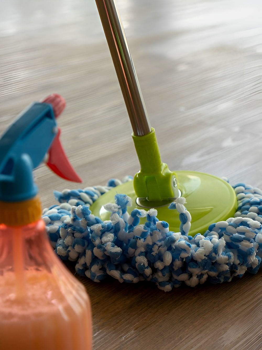 A Mop Is Sitting On A Wooden Floor Next To A Spray Bottle — DP Cleaning Supplies Pty Ltd In Mareeba, QLD
