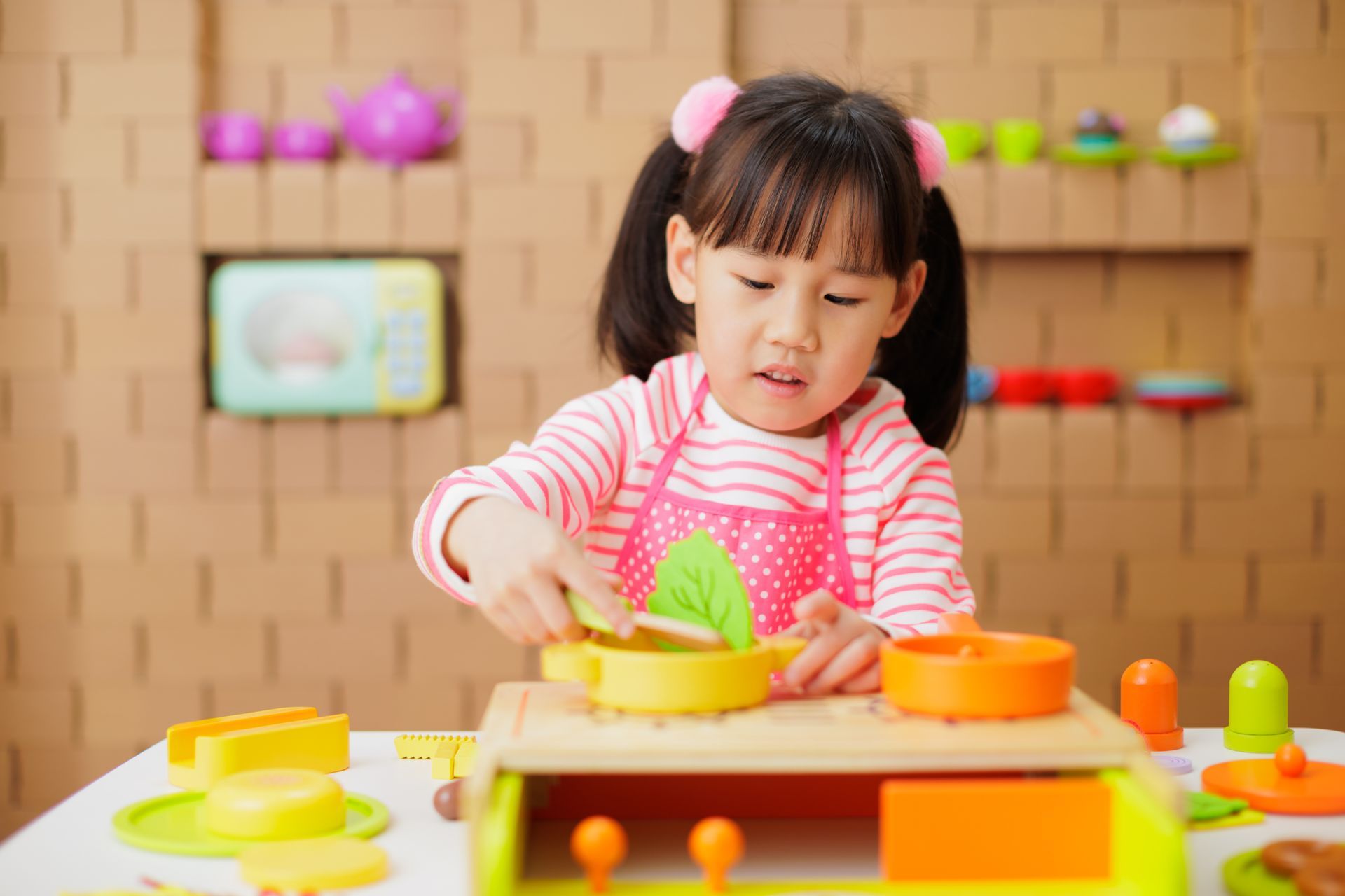 Little girl playing with toy dishes and stacking blocks in a playroom. Little girl playing with toy dishes and stacking blocks in a playroom.