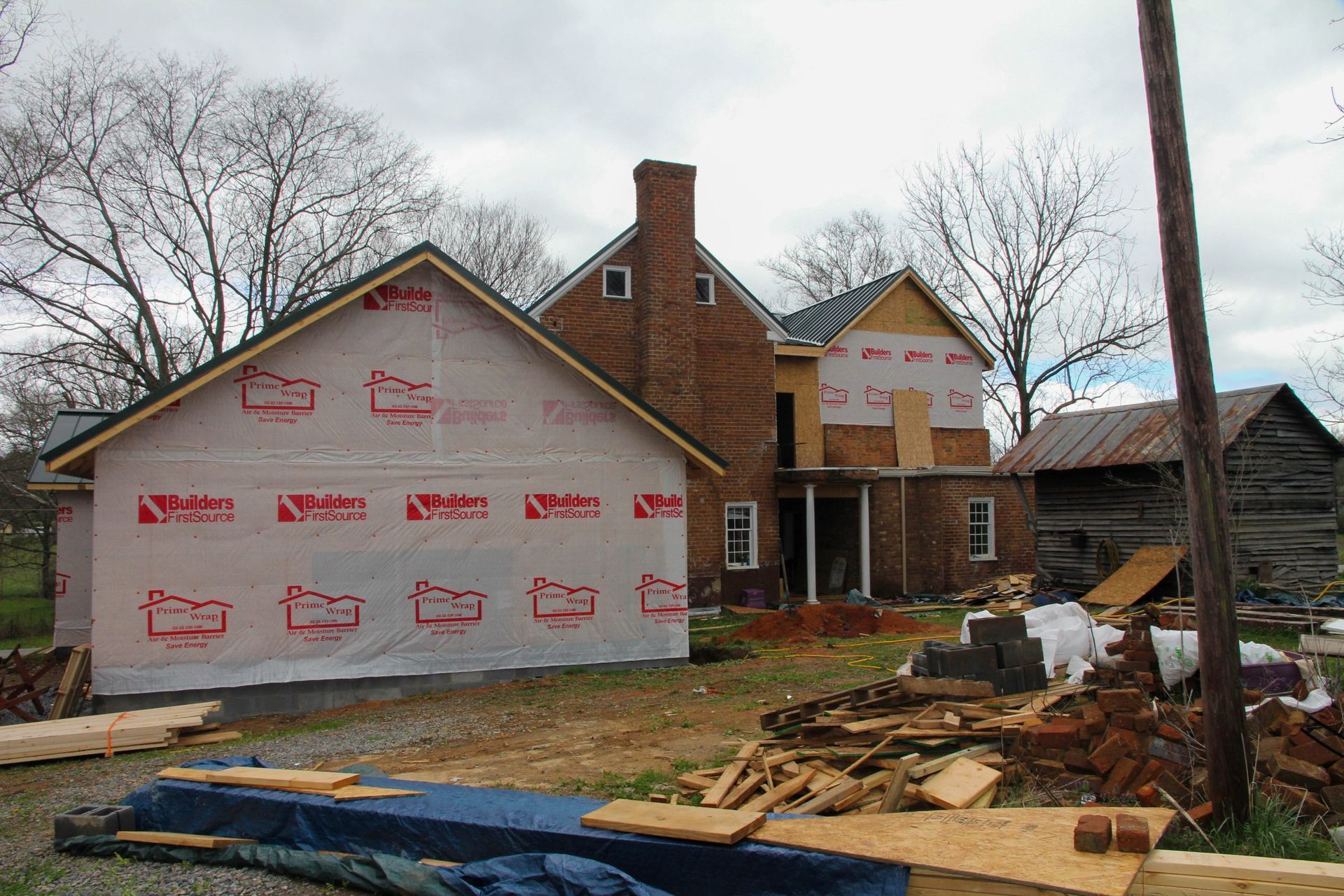 House under construction with pink house wrap, brick chimney, and debris in front yard