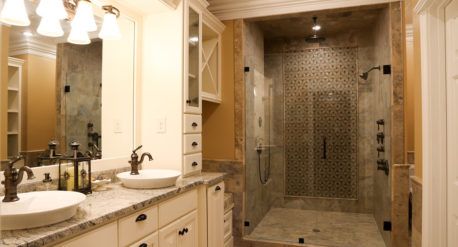 Luxury bathroom with double vanity, ornate mirrors, and glass-enclosed tiled shower