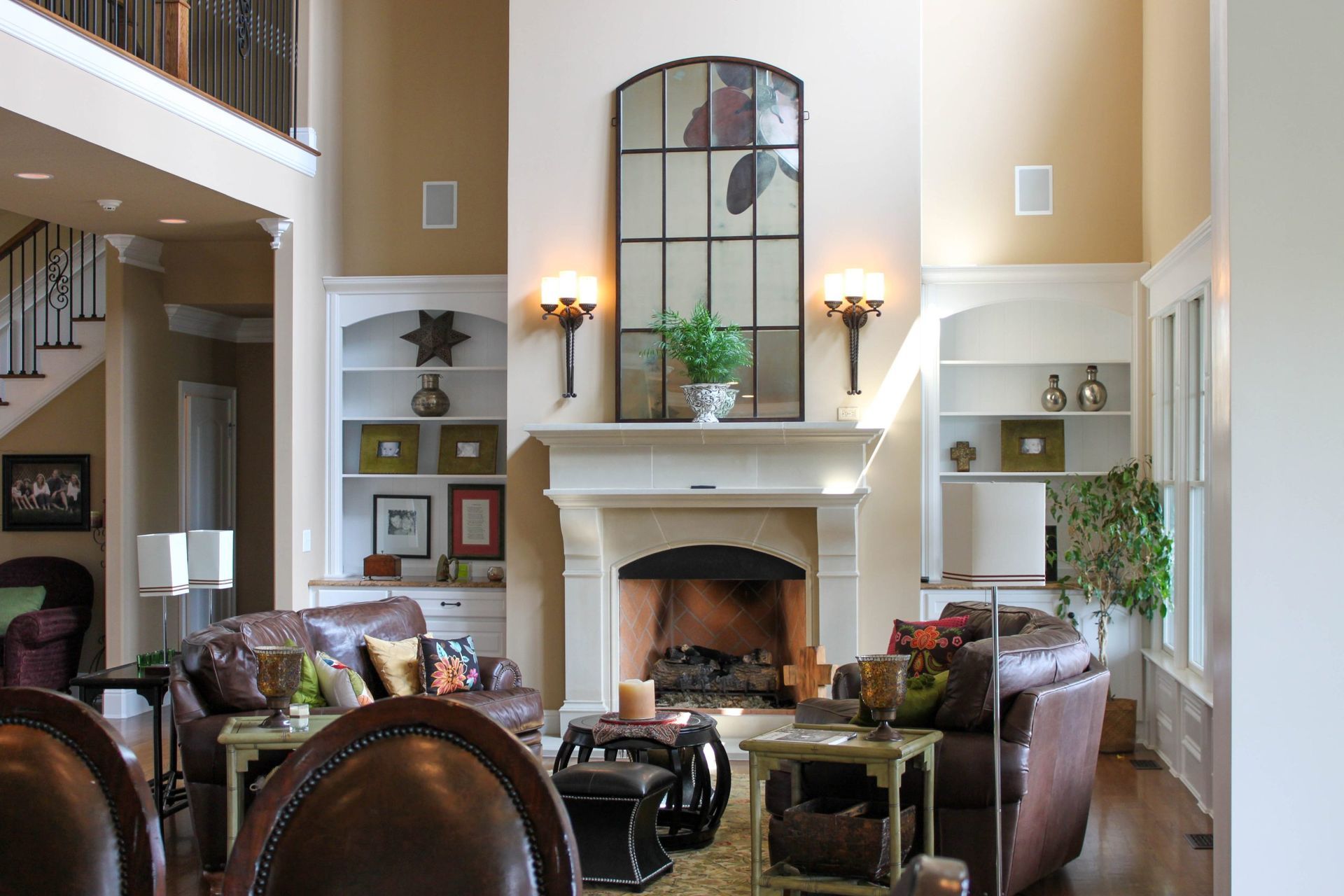 Elegant living room with fireplace, high windows, and leather chairs in warm neutral tones