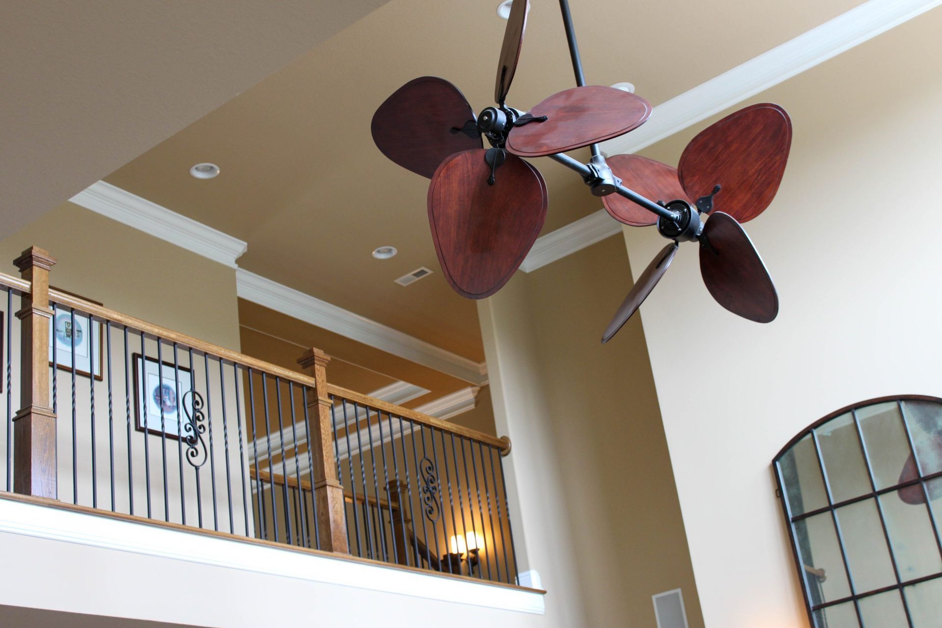 Stairway with wood railing and ceiling fan in a bright home interior