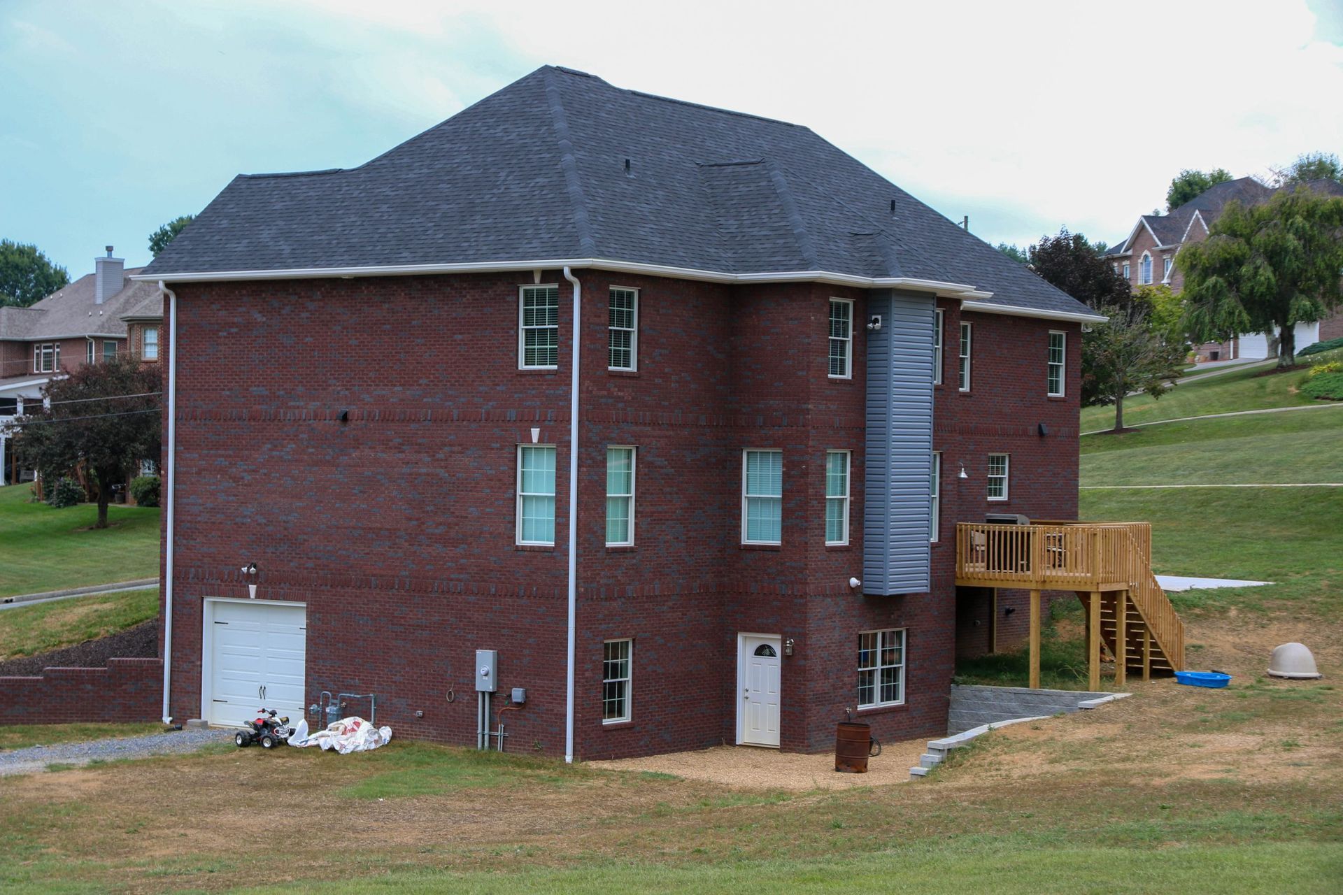 Brick two-story house with dark roof and blue siding accents on a grassy lot