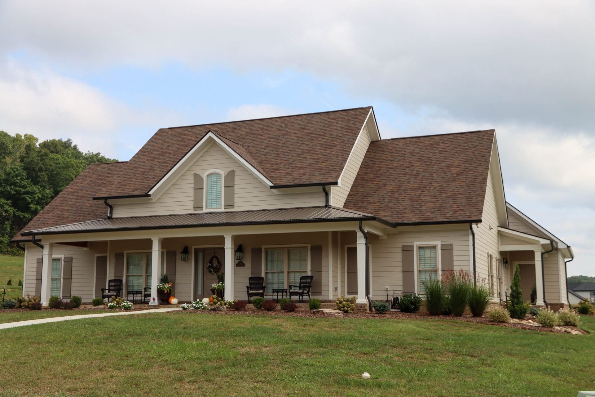 Single-story beige suburban house with brown roof and a front porch on a grassy lawn