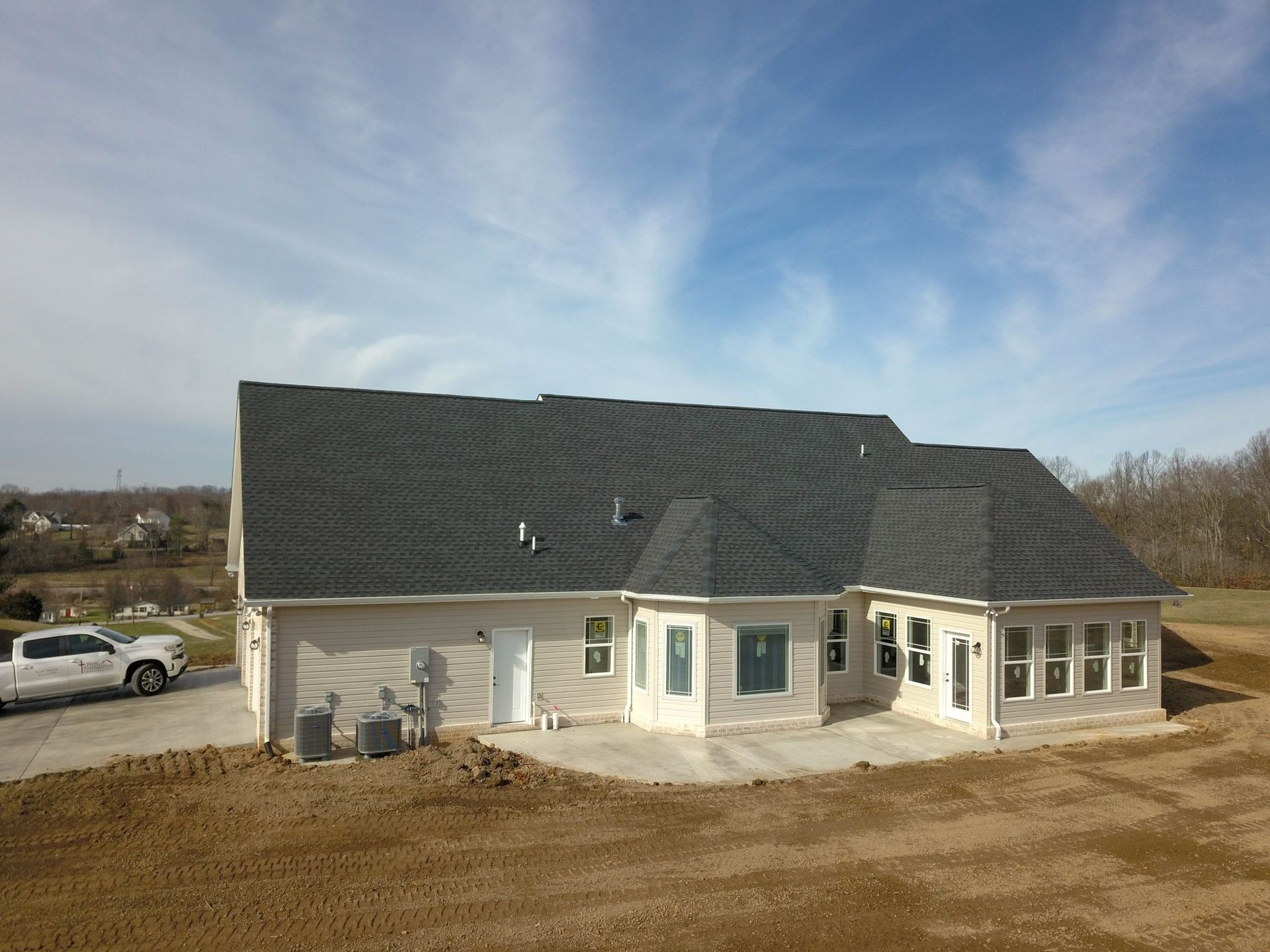 White house with dark roof in a rural setting under a blue sky