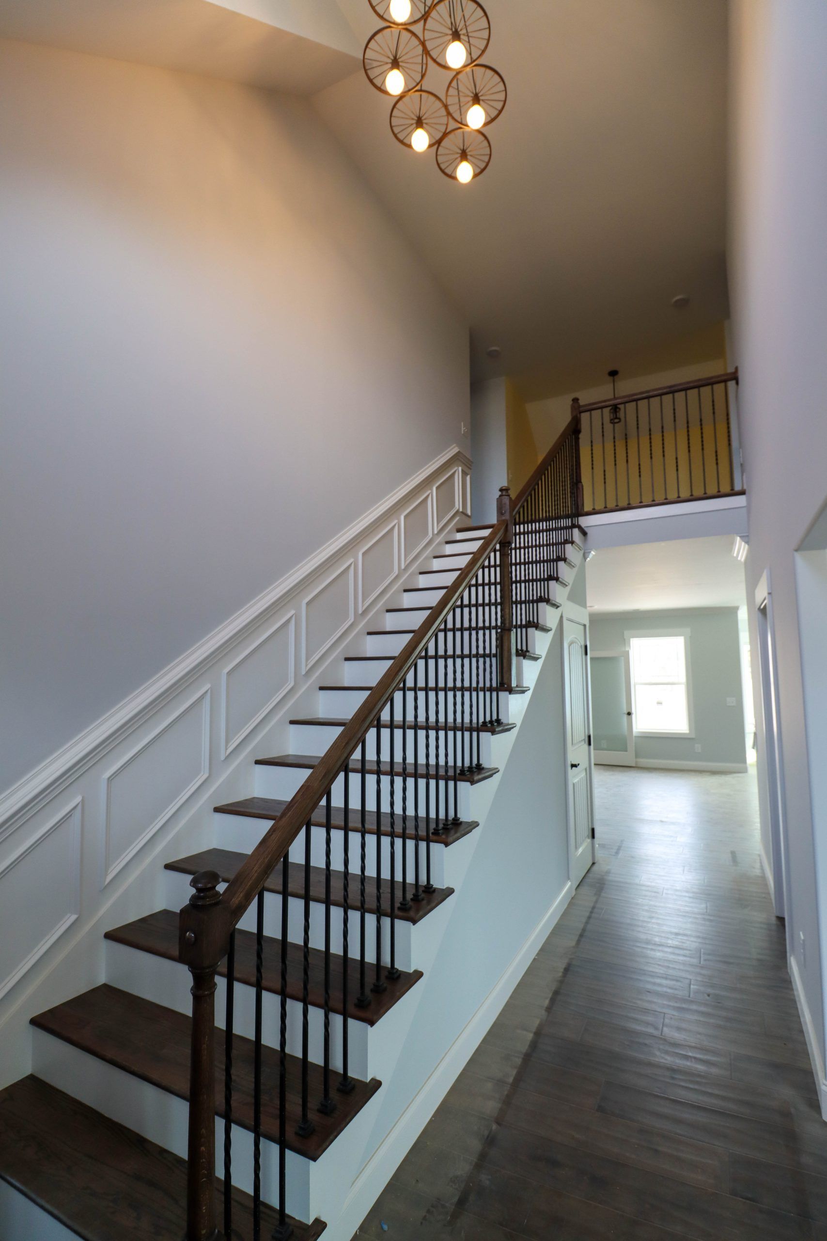 Interior hallway with a staircase, white walls, dark wood steps, and a chandelier.