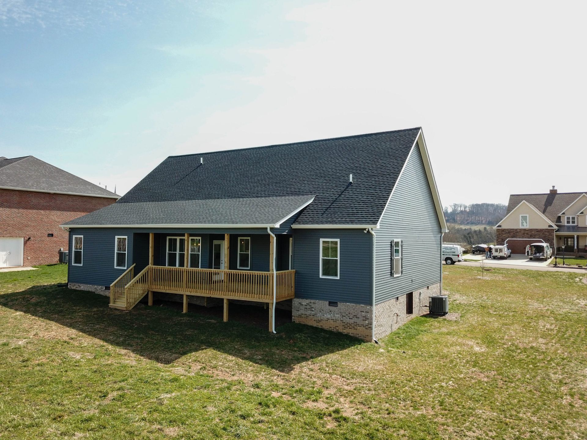Single-story house with dark roof, blue siding, and a small front porch in a suburban neighborhood.