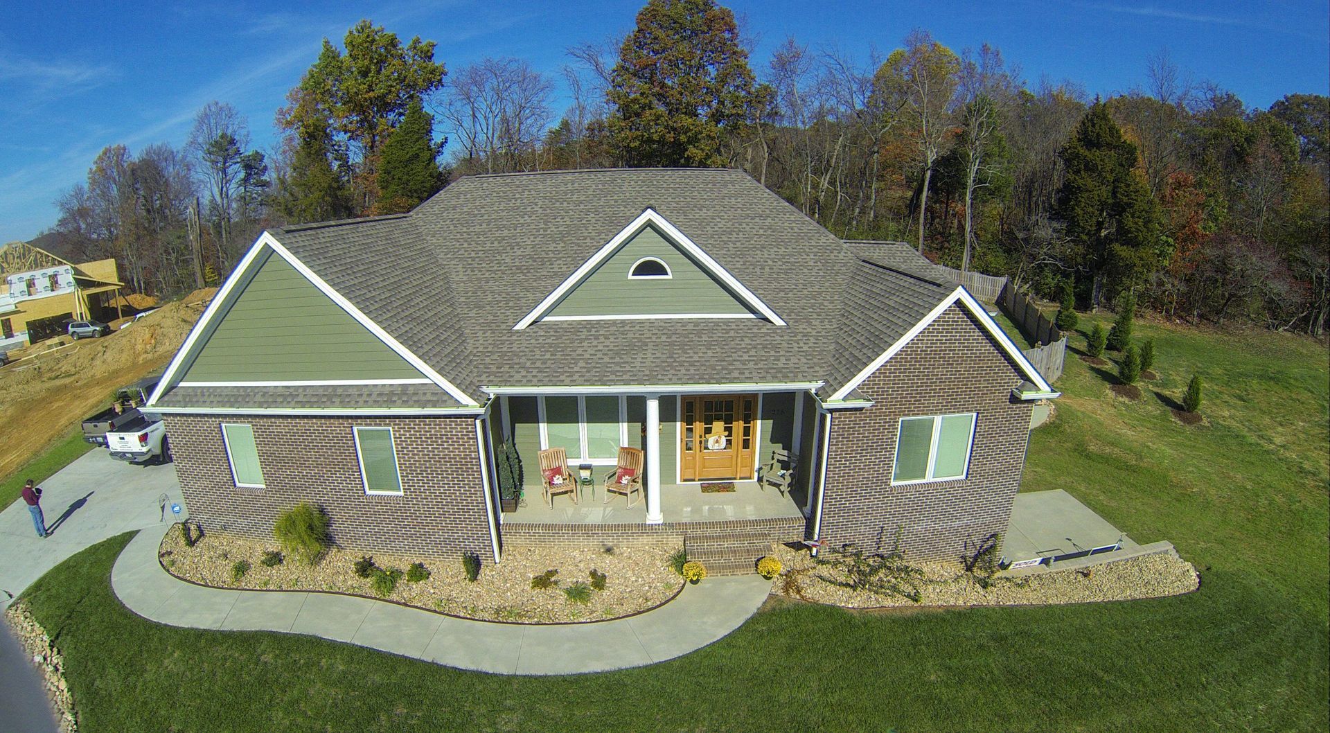 Single-story gray house with green shutters and white trim, front porch, and curved walkway in a grassy yard.