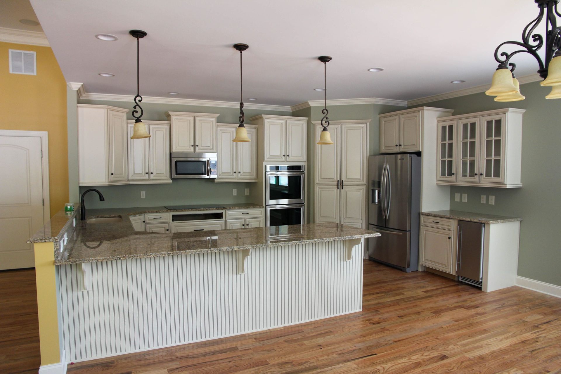 Bright kitchen with white cabinets, marble island, stainless fridge, and hardwood floors