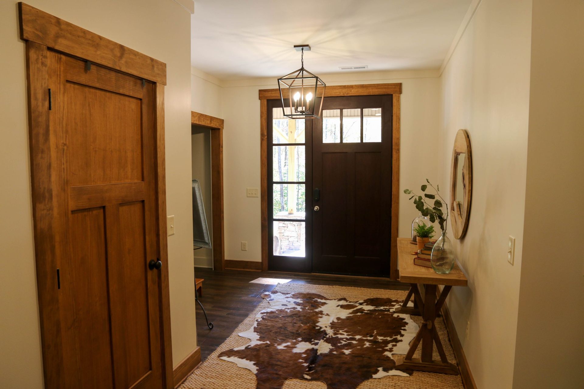 Entry hallway with wood front door, hanging lantern, and cowhide rug on the floor.
