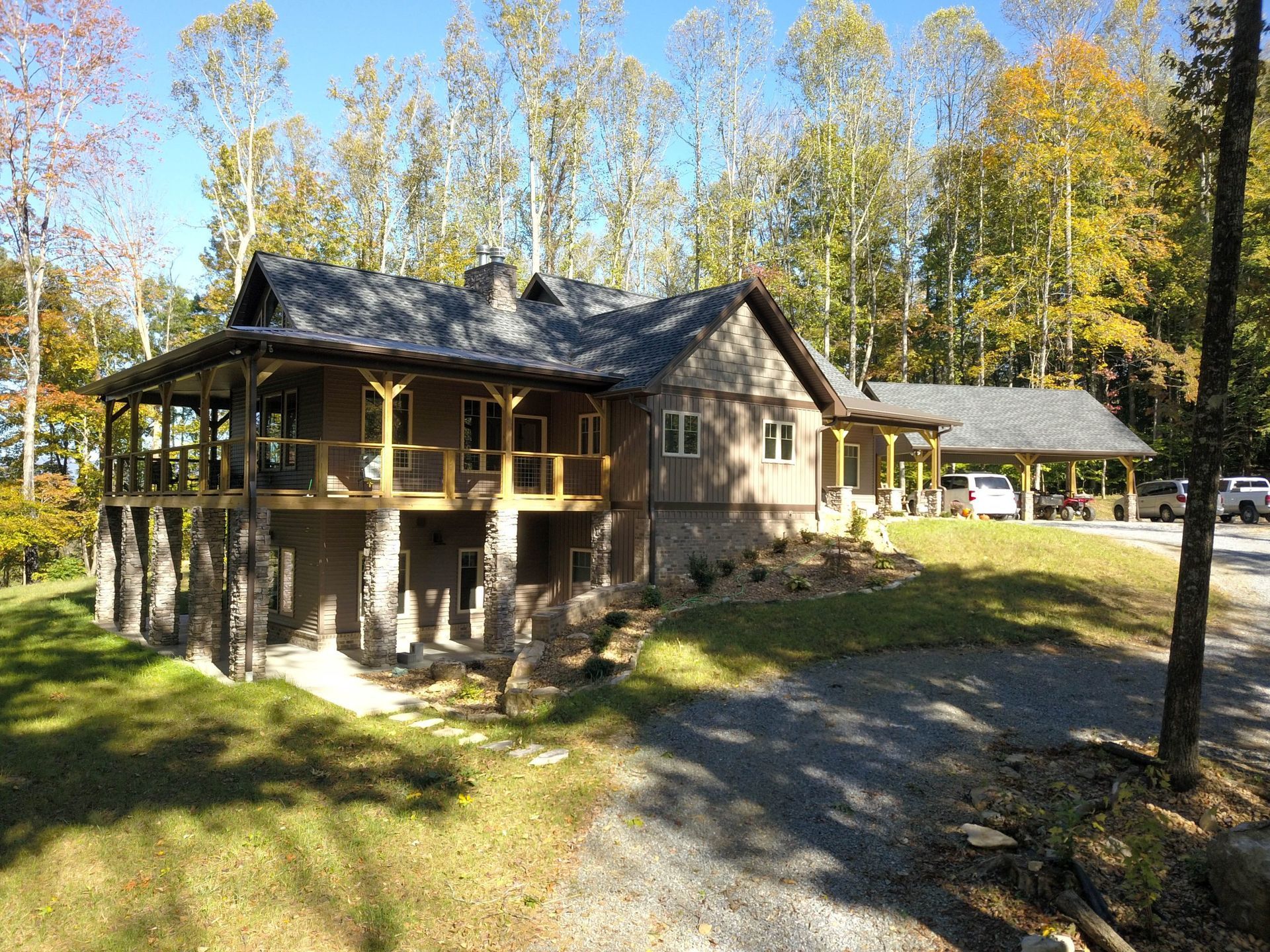 Wooden house with wraparound porch in a sunny autumn forest clearing