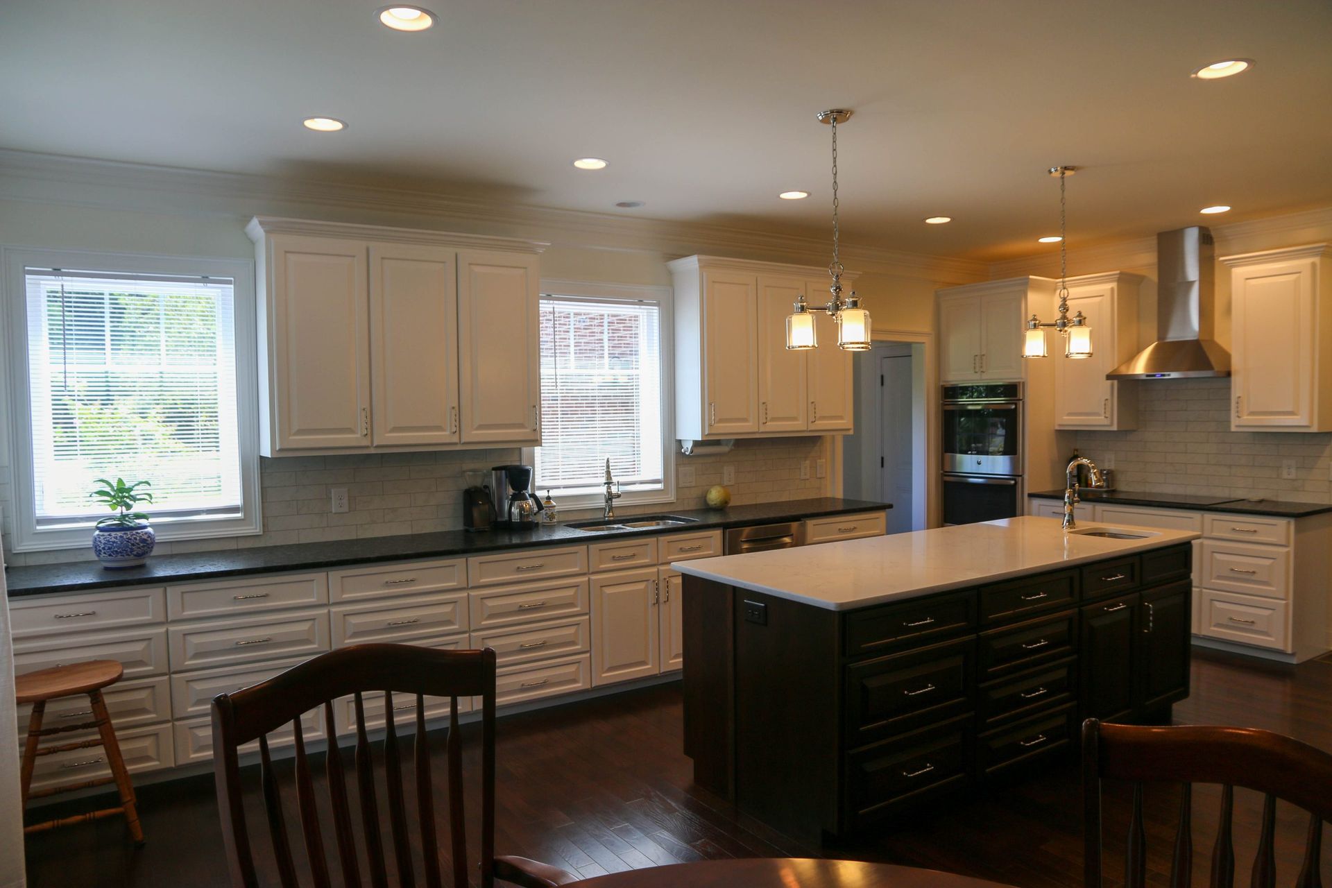 Bright modern kitchen with white cabinets, black countertops, island, and hardwood floors