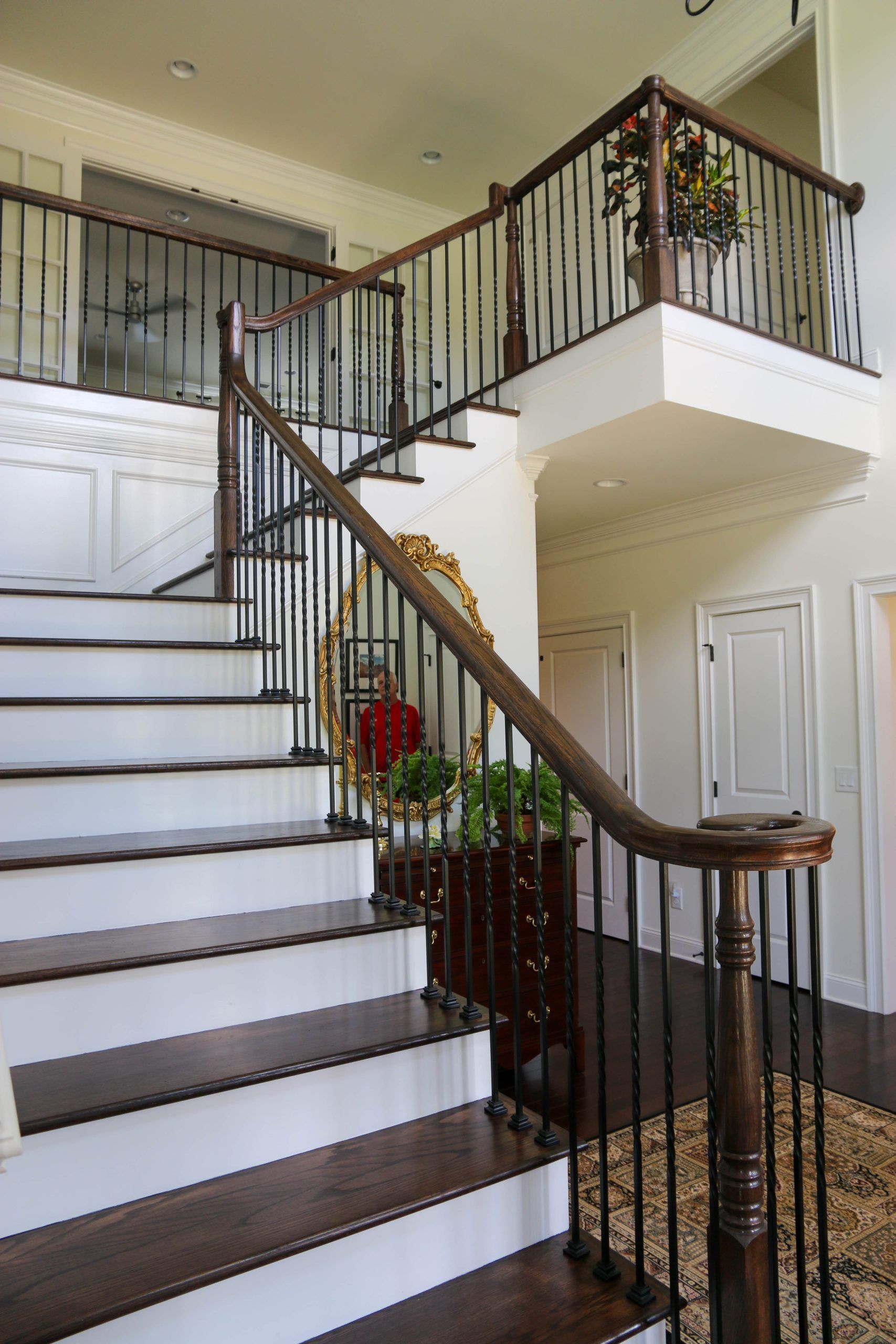 Interior staircase with dark wood railings and white steps in a bright foyer