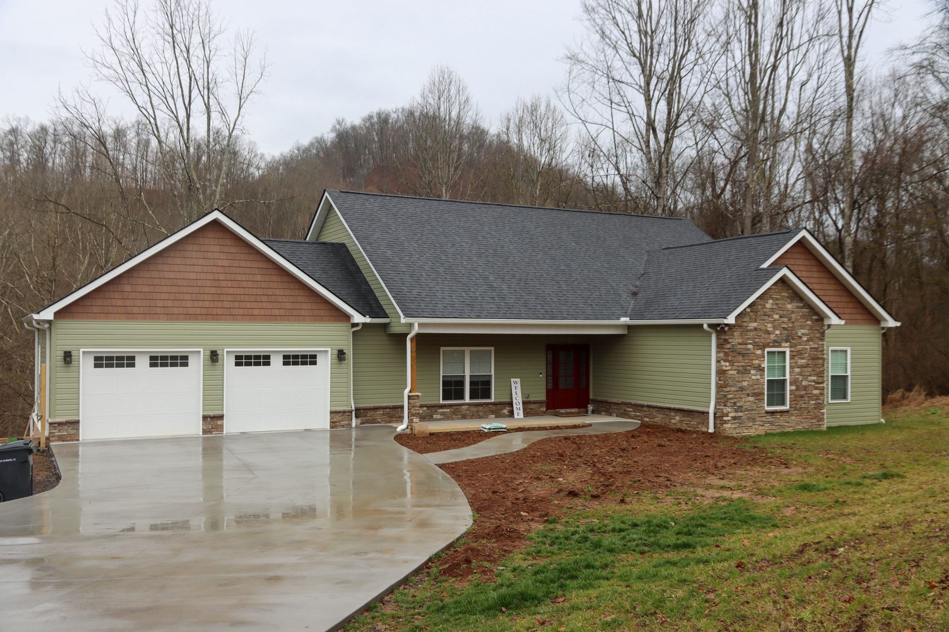 Suburban house with two-car garage, wet driveway, and overcast sky