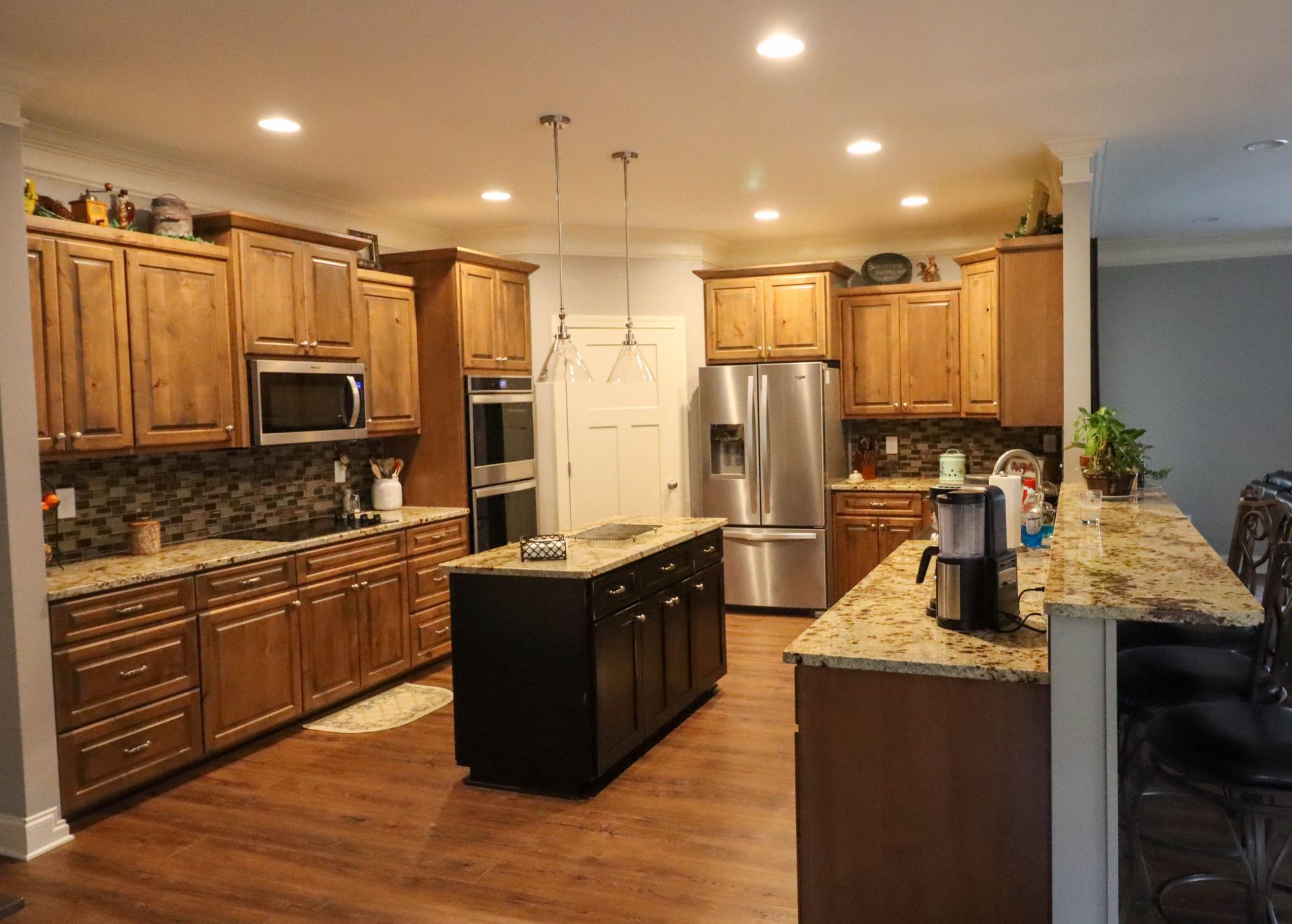 Spacious kitchen with wooden cabinets, stainless steel appliances, and a central island under warm lighting