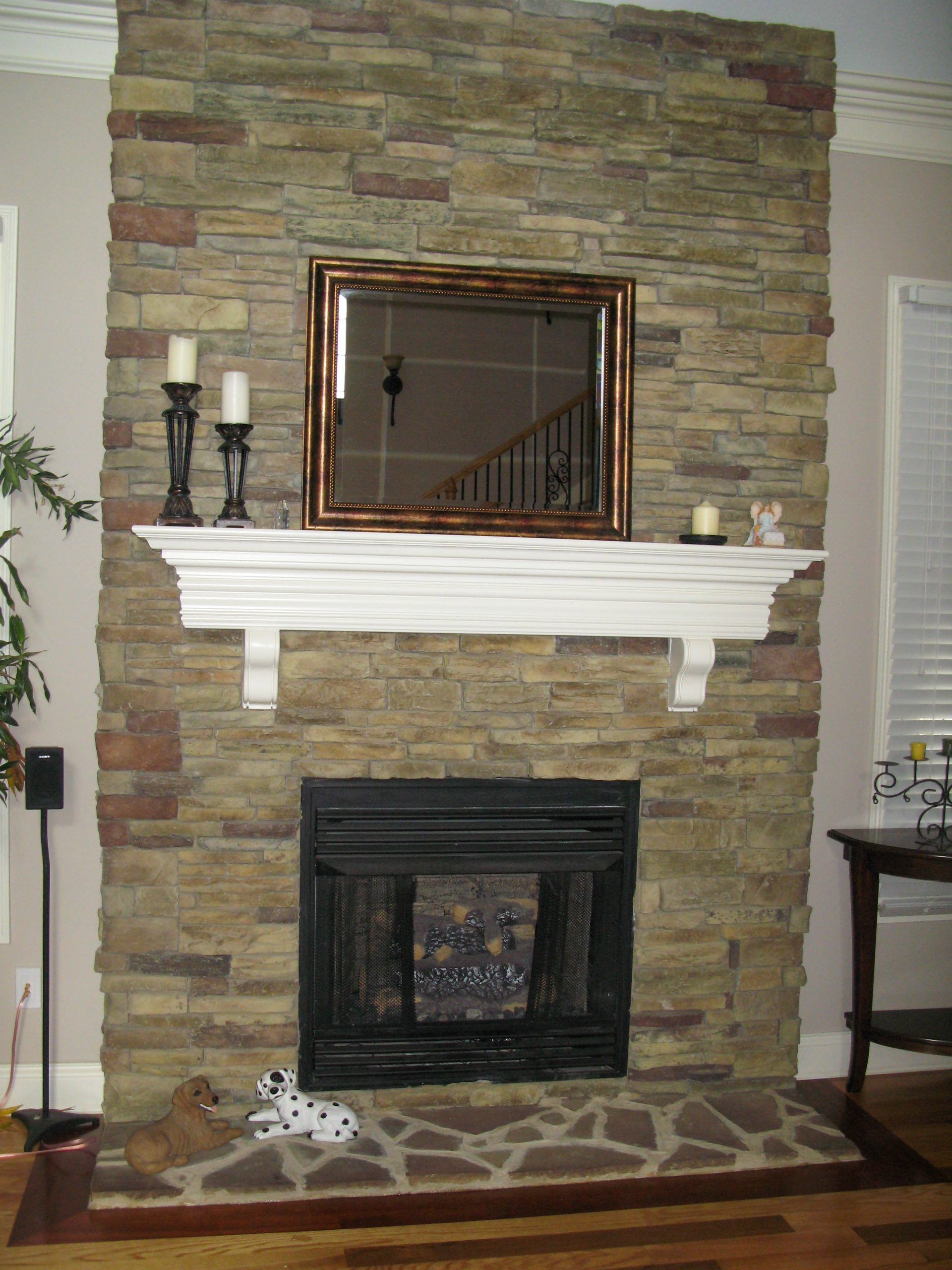 Stone fireplace with mirror, white mantel, and candleholders in a living room