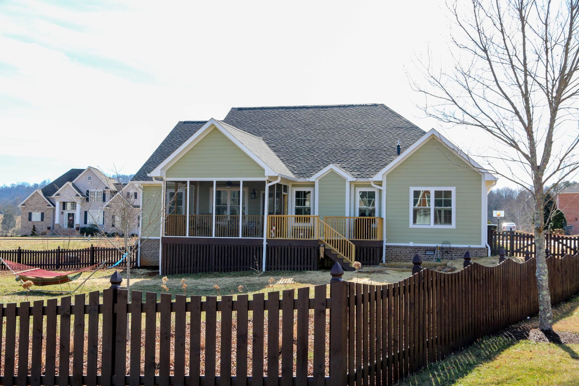Suburban house with a front porch and brown picket fence on a sunny day