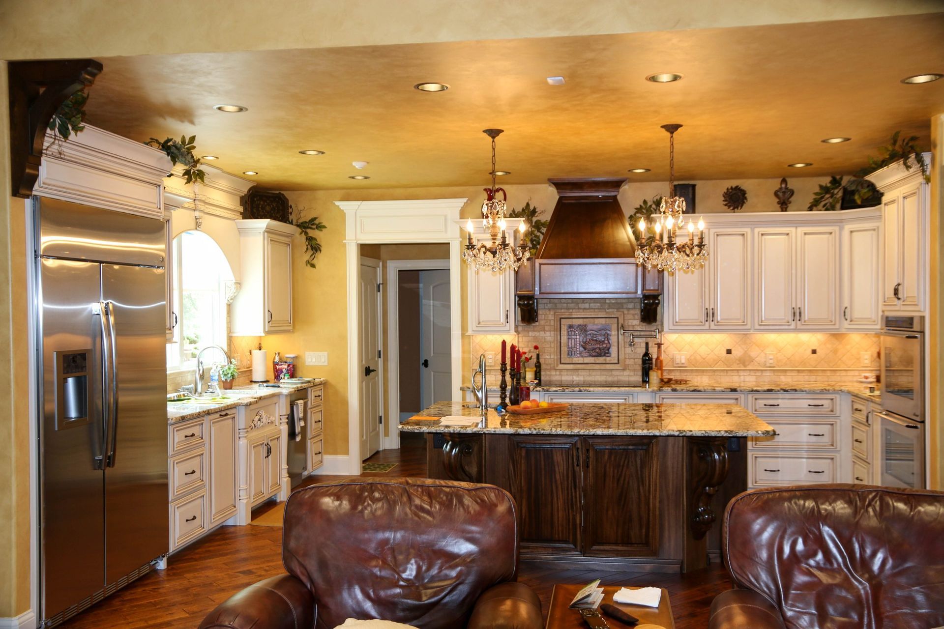 Luxury kitchen with stainless steel appliances, marble island, and leather chairs in the foreground
