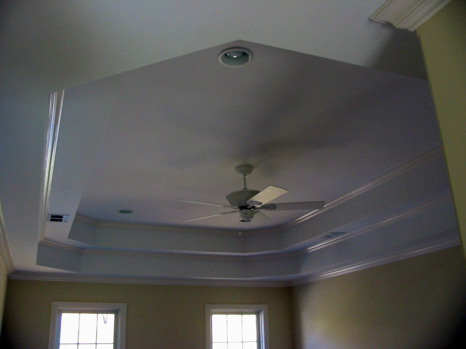 Living room ceiling with recessed trim, central ceiling fan, and two small windows below