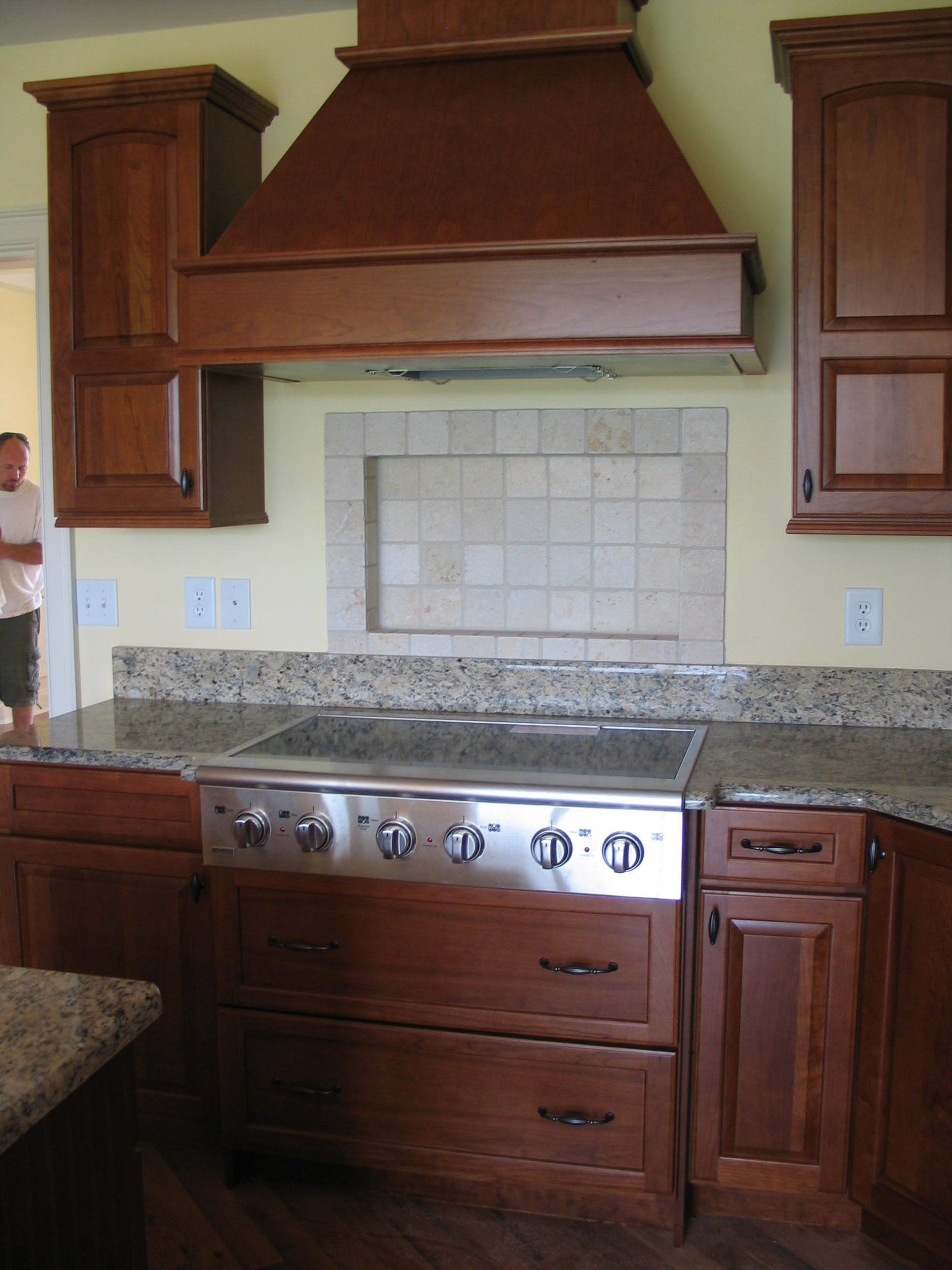 Kitchen with wood cabinets, granite countertop, and stainless steel stove beneath a large copper range hood