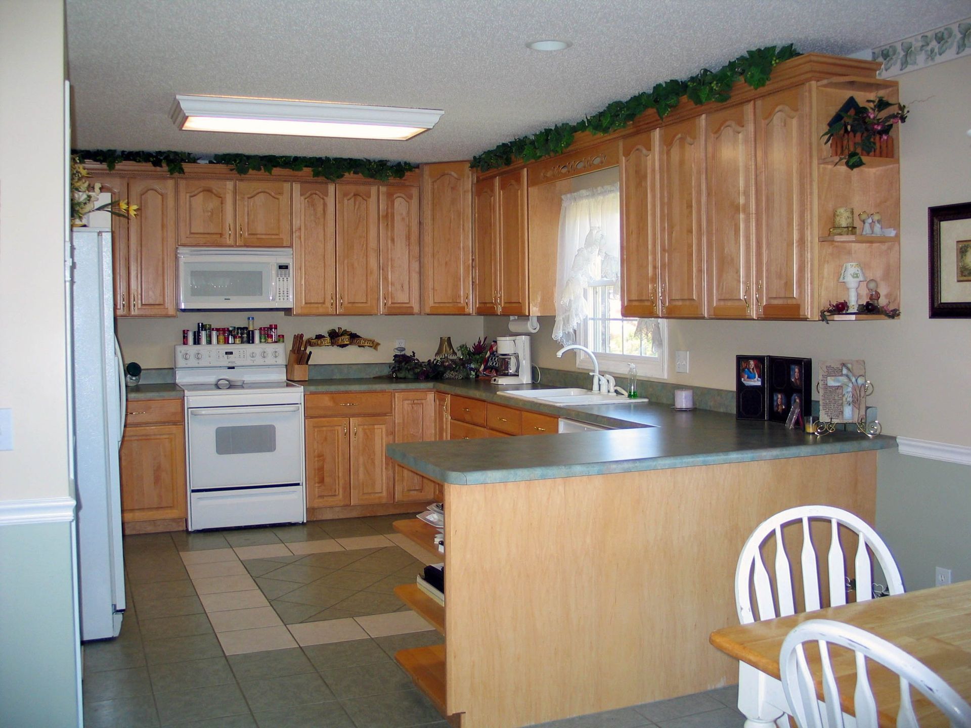 Bright kitchen with wood cabinets, white appliances, tiled floor, and a center island.