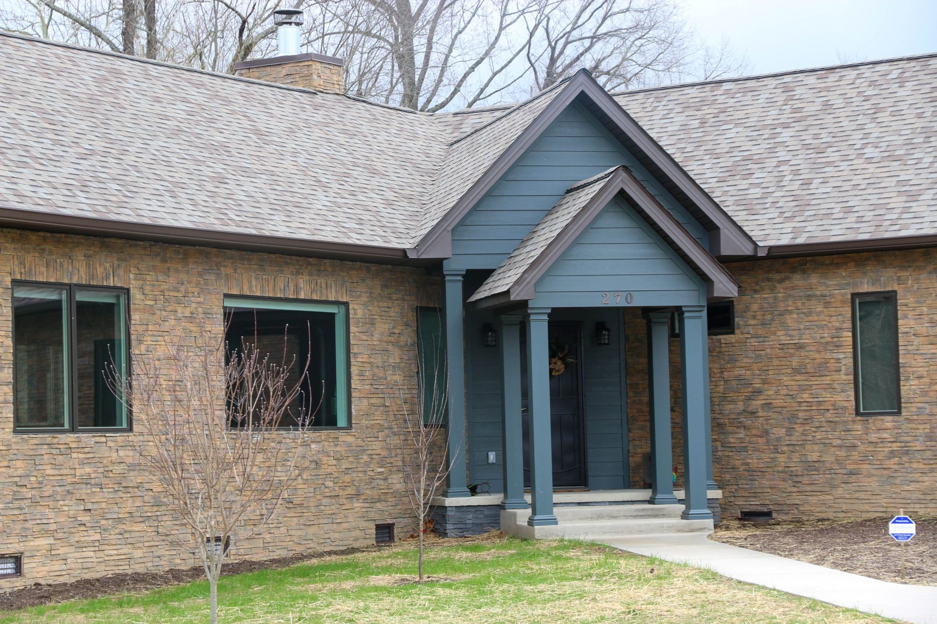 Brick house entrance with blue-trimmed covered porch and walkway leading to the front door