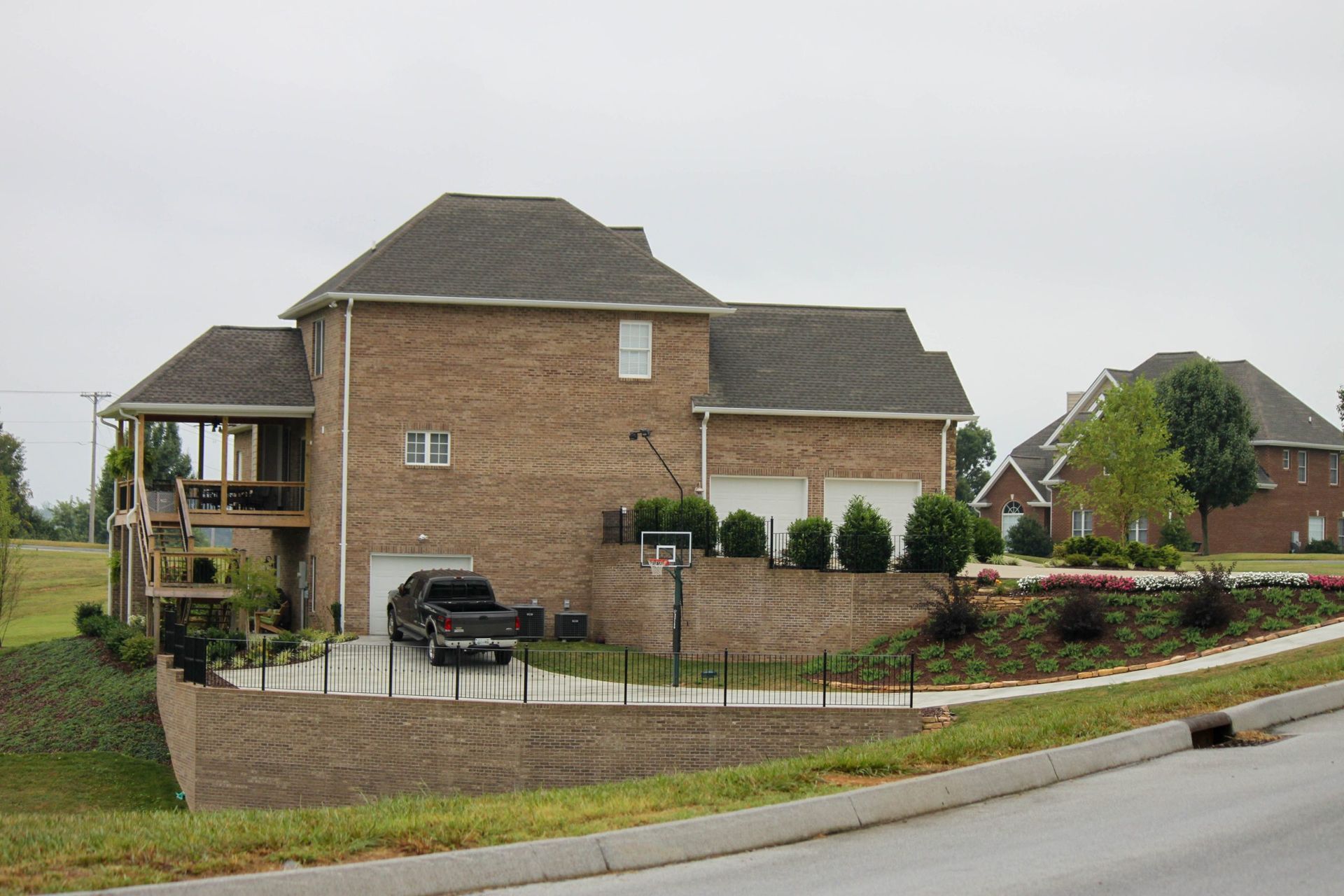 Brick suburban house with attached garage, driveway, and landscaped front yard on a quiet street
