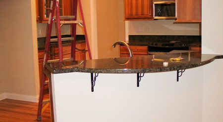 Kitchen with granite island, wooden cabinets, red ladder, and stainless steel appliances